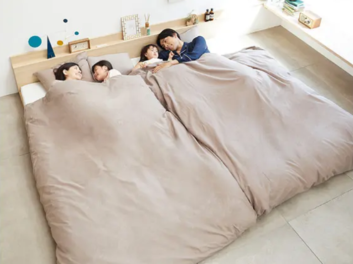 家族3・4人がベッドで寝ている画像